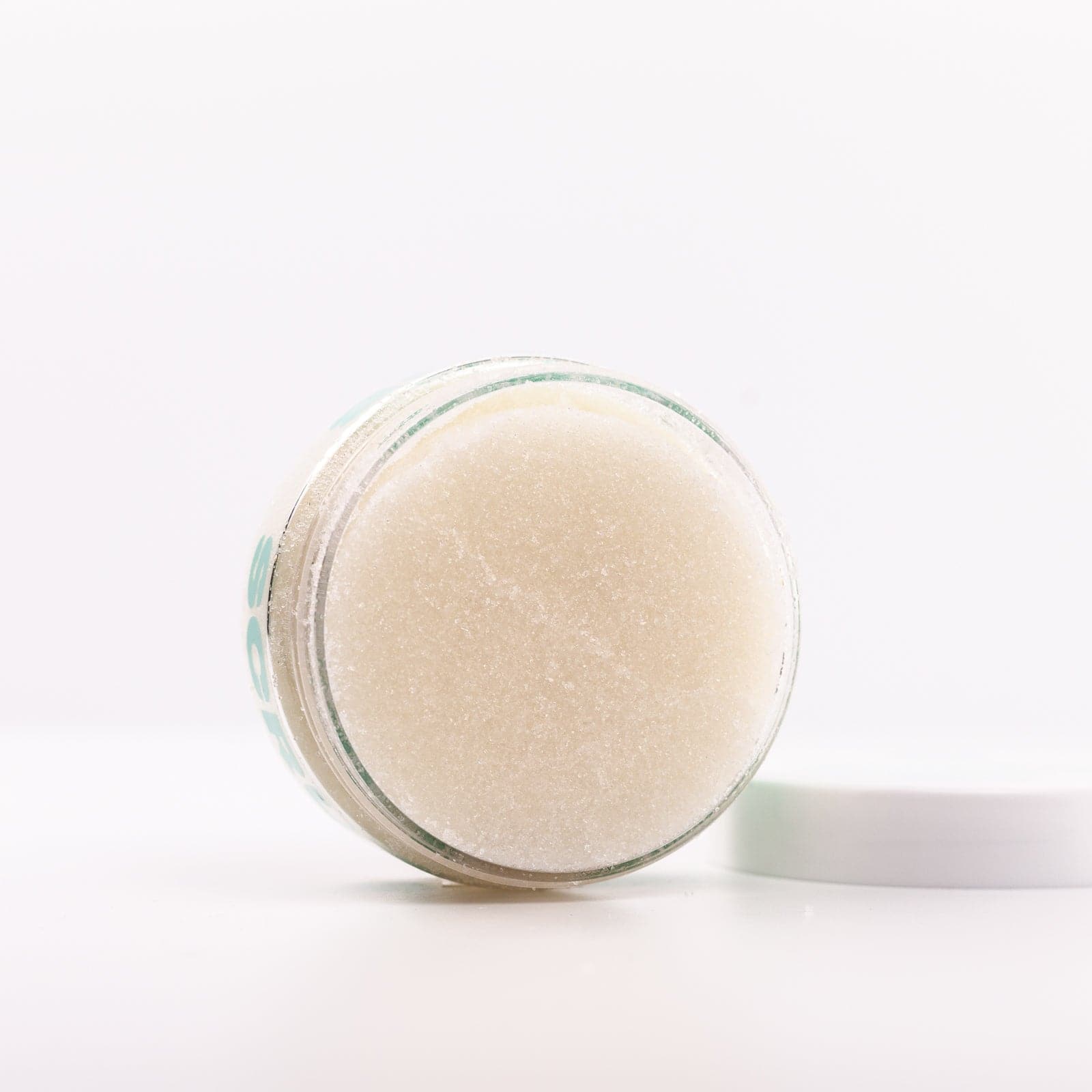 Clear Body Scrub container standing on side with lid off against white background