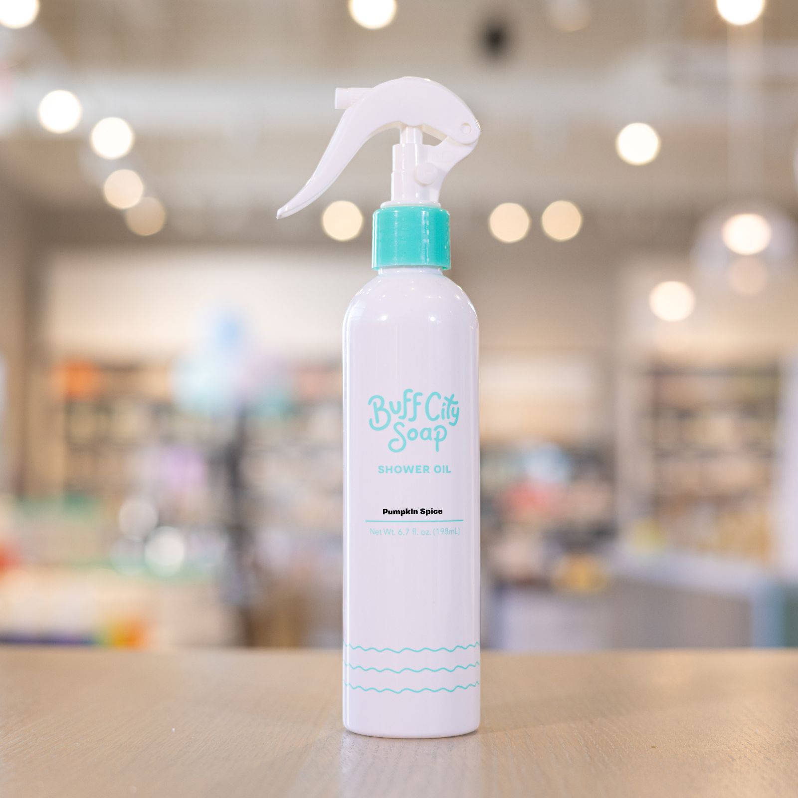 Pumpkin Spice Shower Oil spray bottle with teal finishes on wooden counter