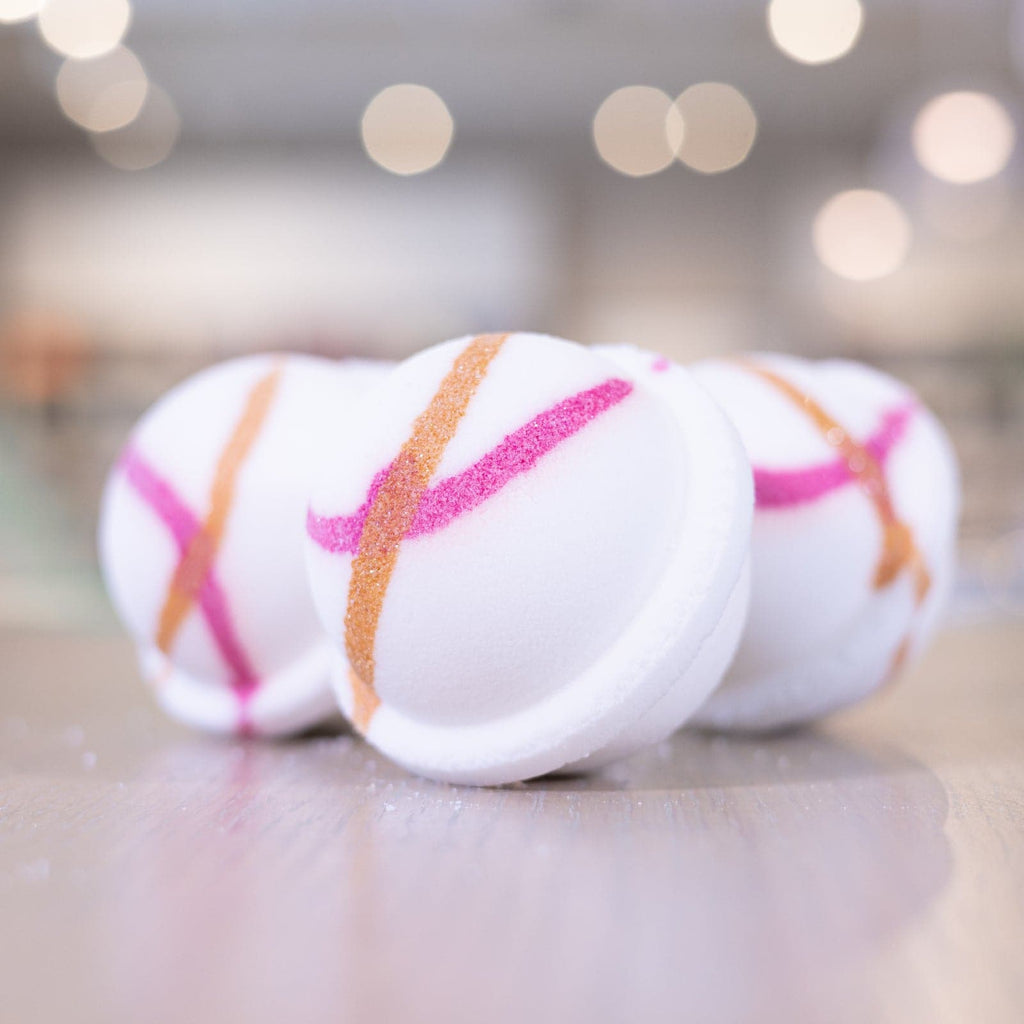Three white bath bombs with orange and pink designs 