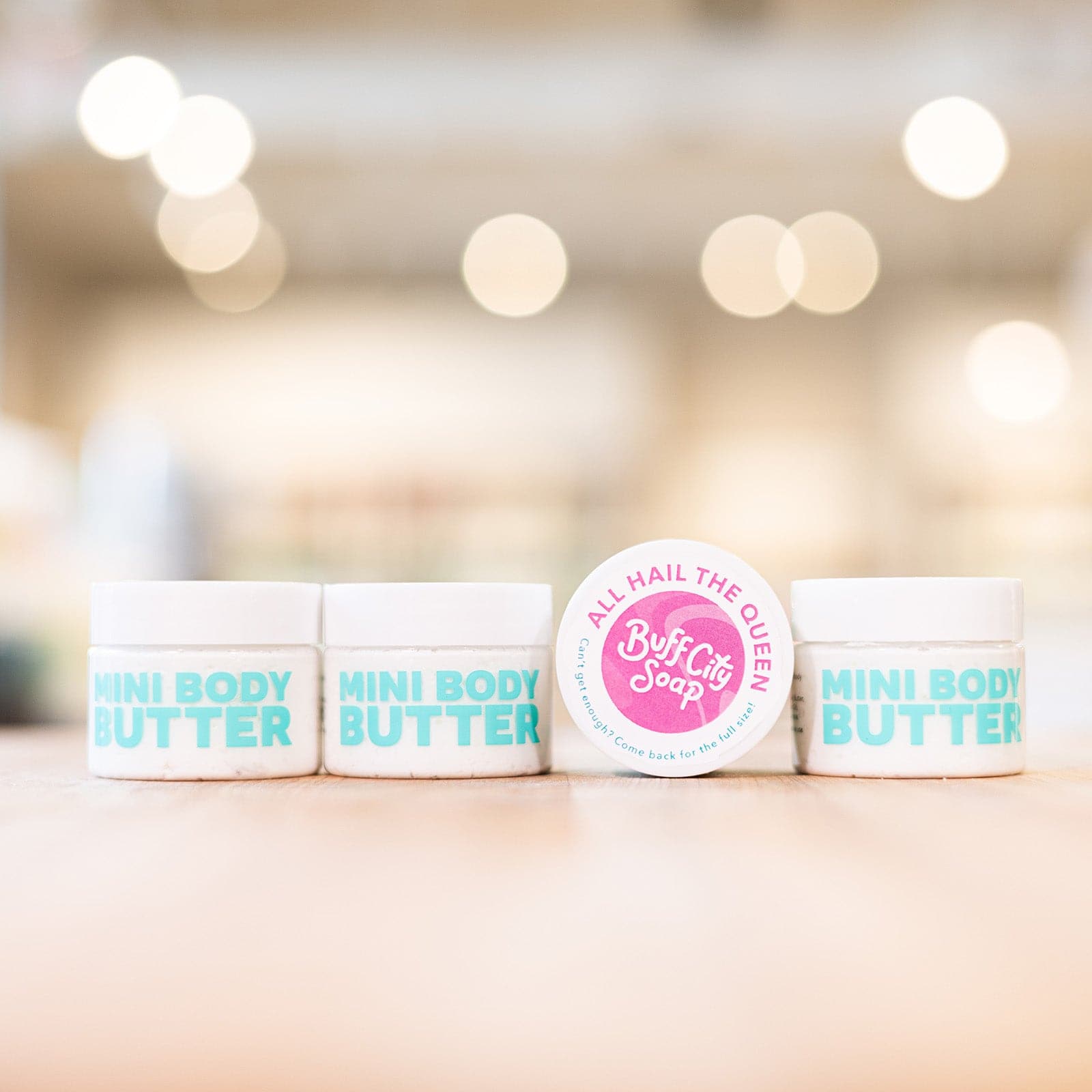 Four white All Hail The Queen Mini Body Butters lined up on counter