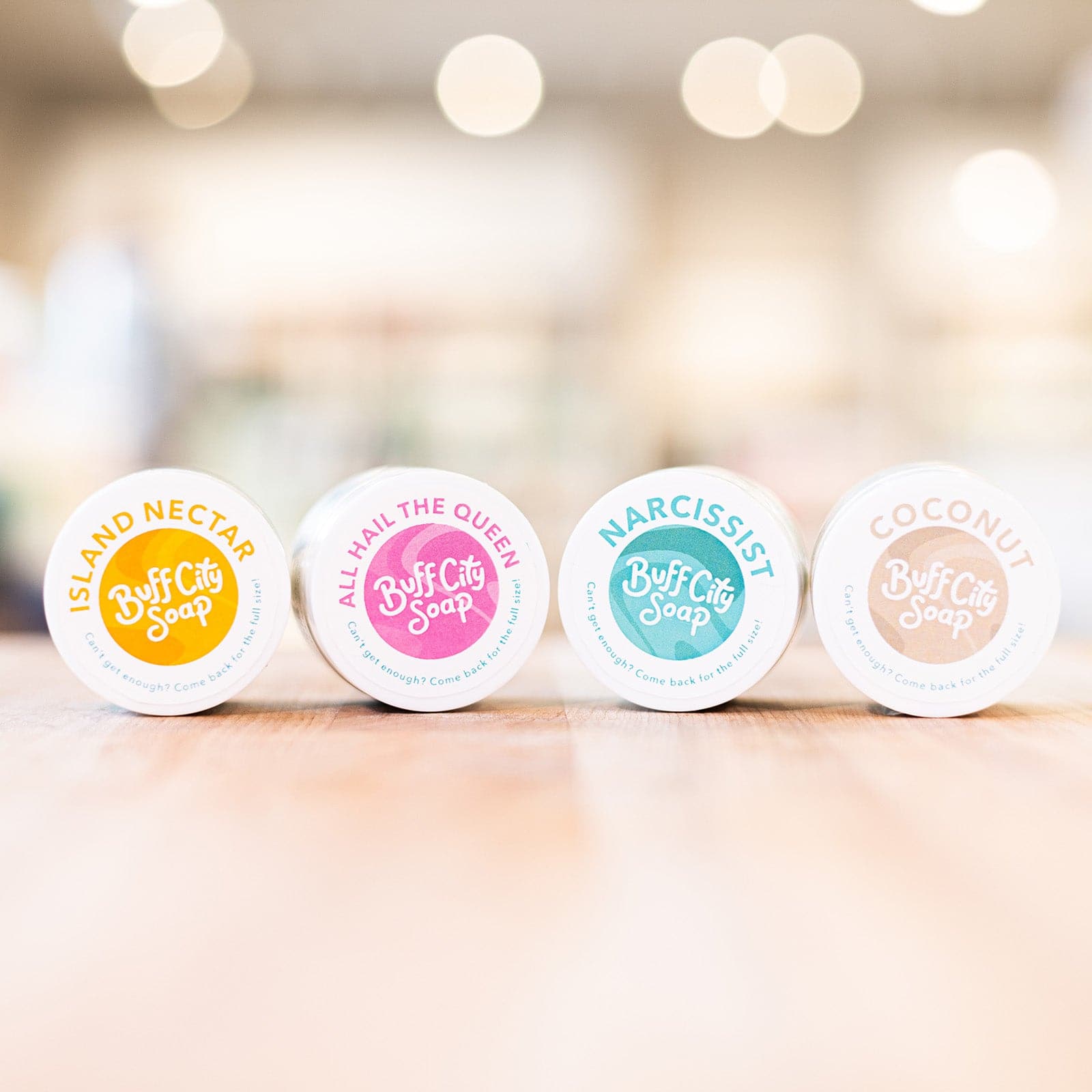 Mini Body Butter containers with multiple colors on side and lined up on counter