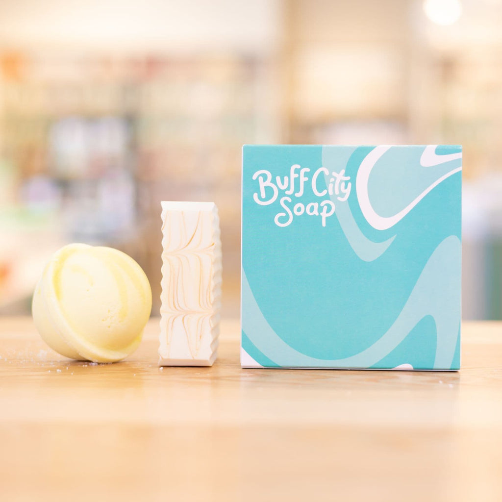Blue 2 piece gift set packaging with yellow bath bomb and white soap bar on counter