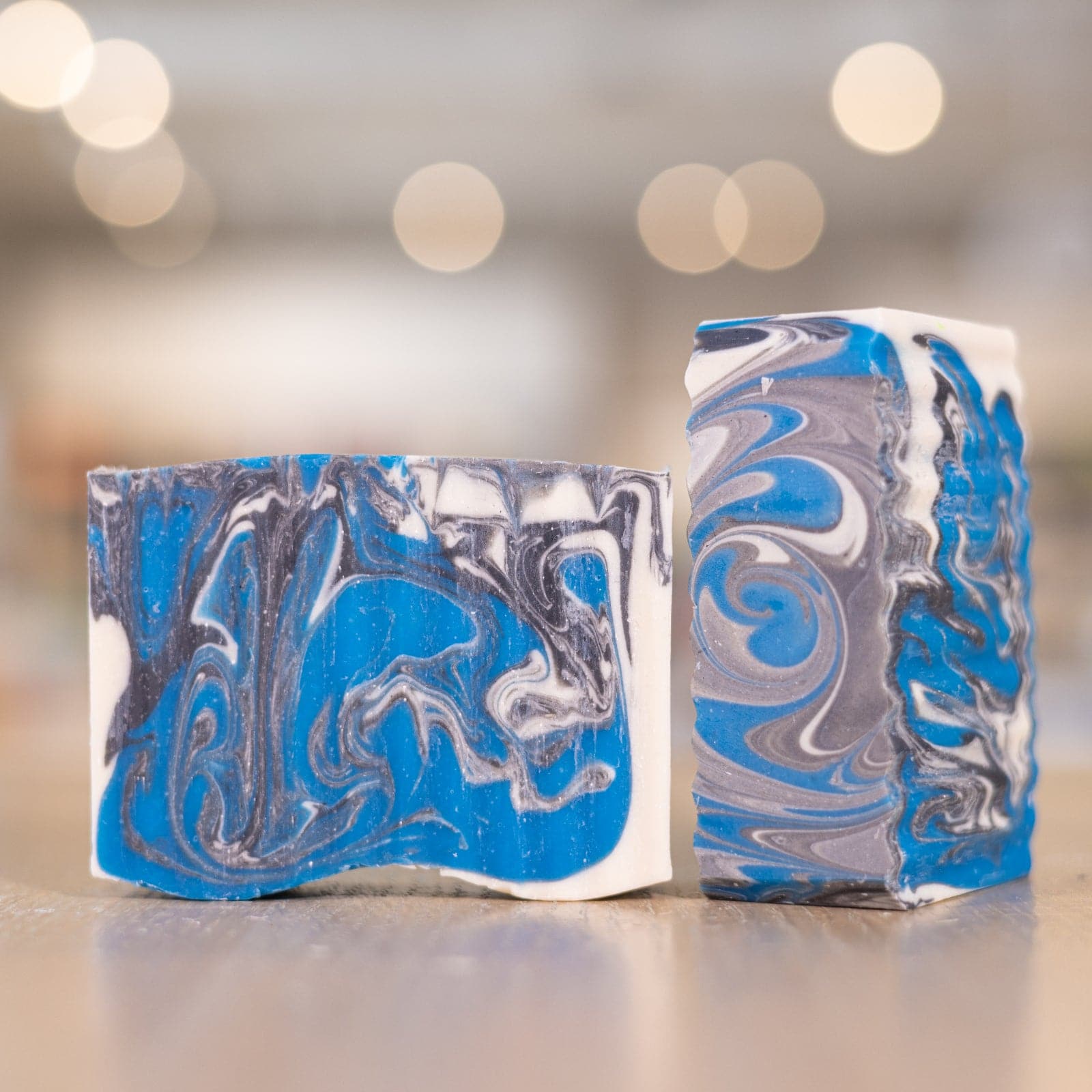 Two Hey Headache Soap Bars with blue and grey swirls on wooden counter