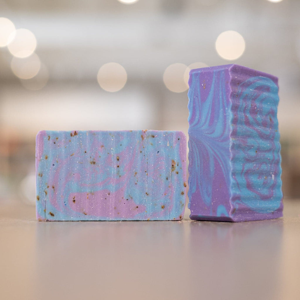 Two bars of Buff City Soap's lavender colored with blue and purple swirls