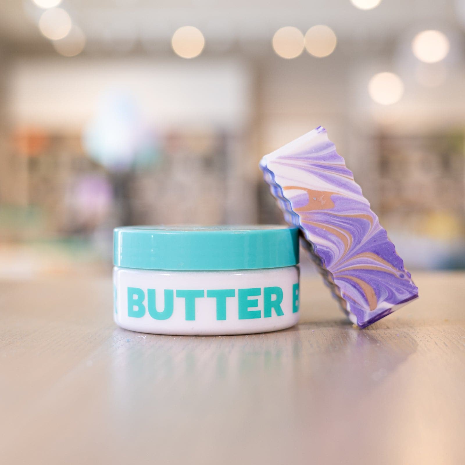 Buff City Soap's love potion body butter with a purple soap bar laying on it