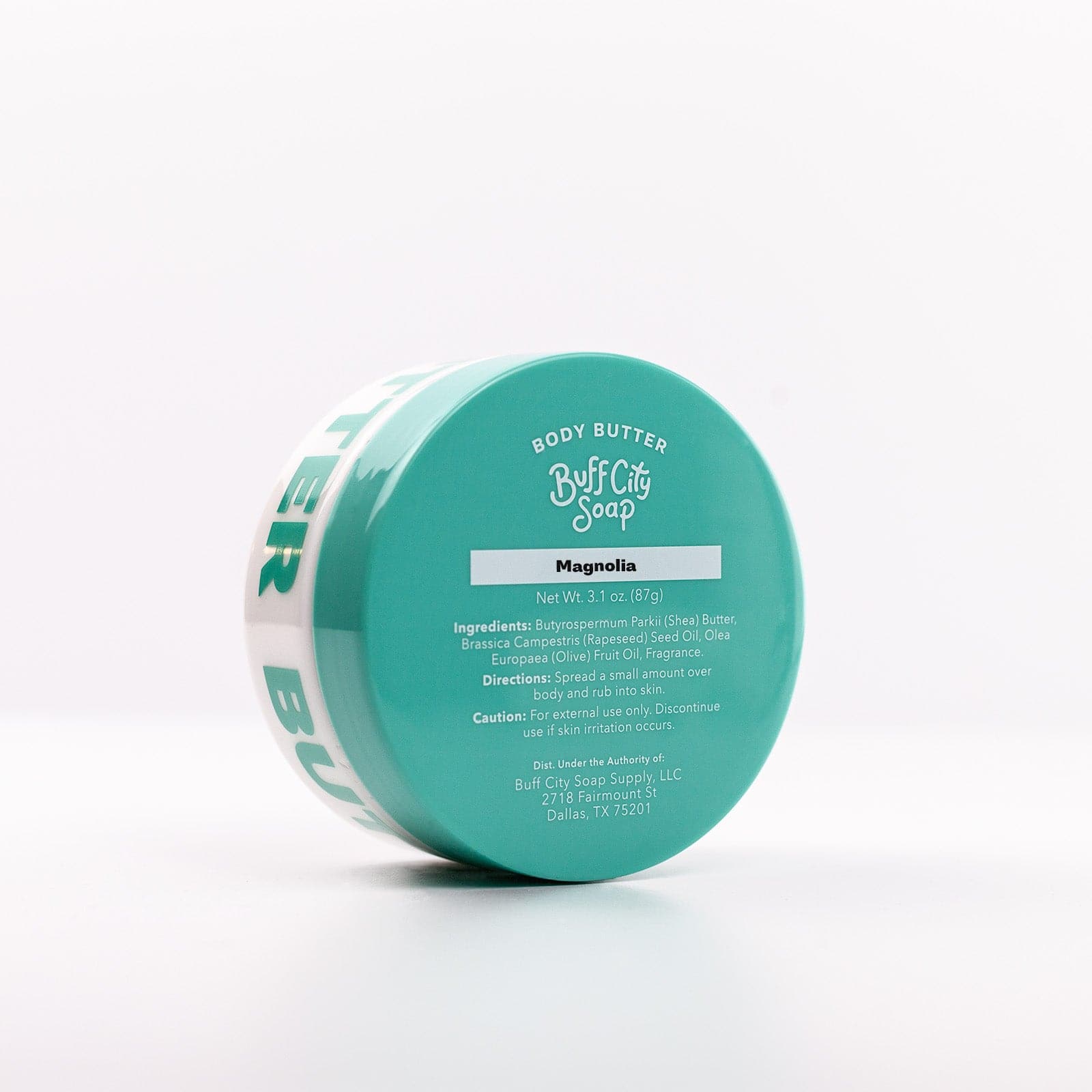 Magnolia Body Butter container with teal lid standing upright and angled against white background