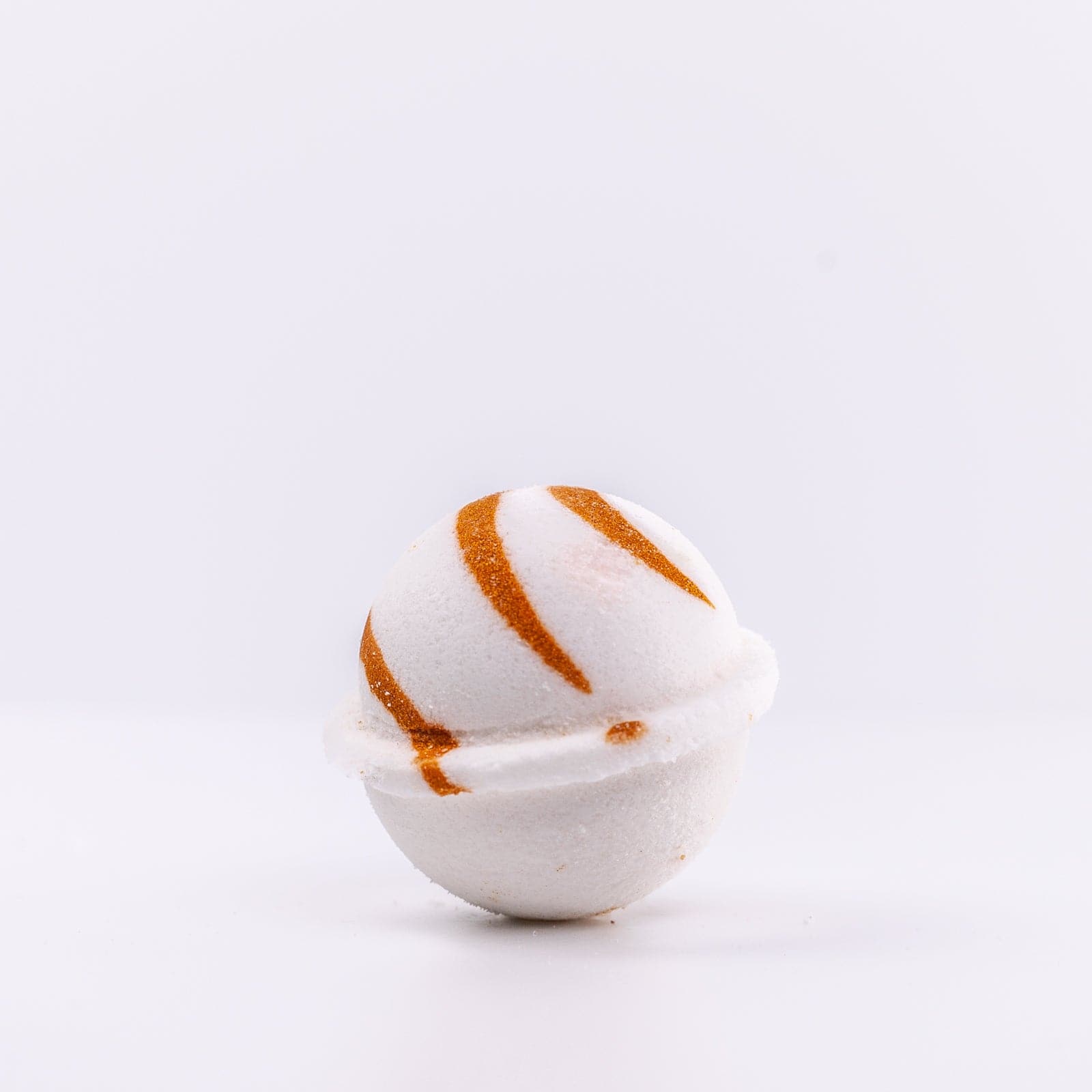 a white Narcissist Bath Bomb, with caramel design, placed upright 