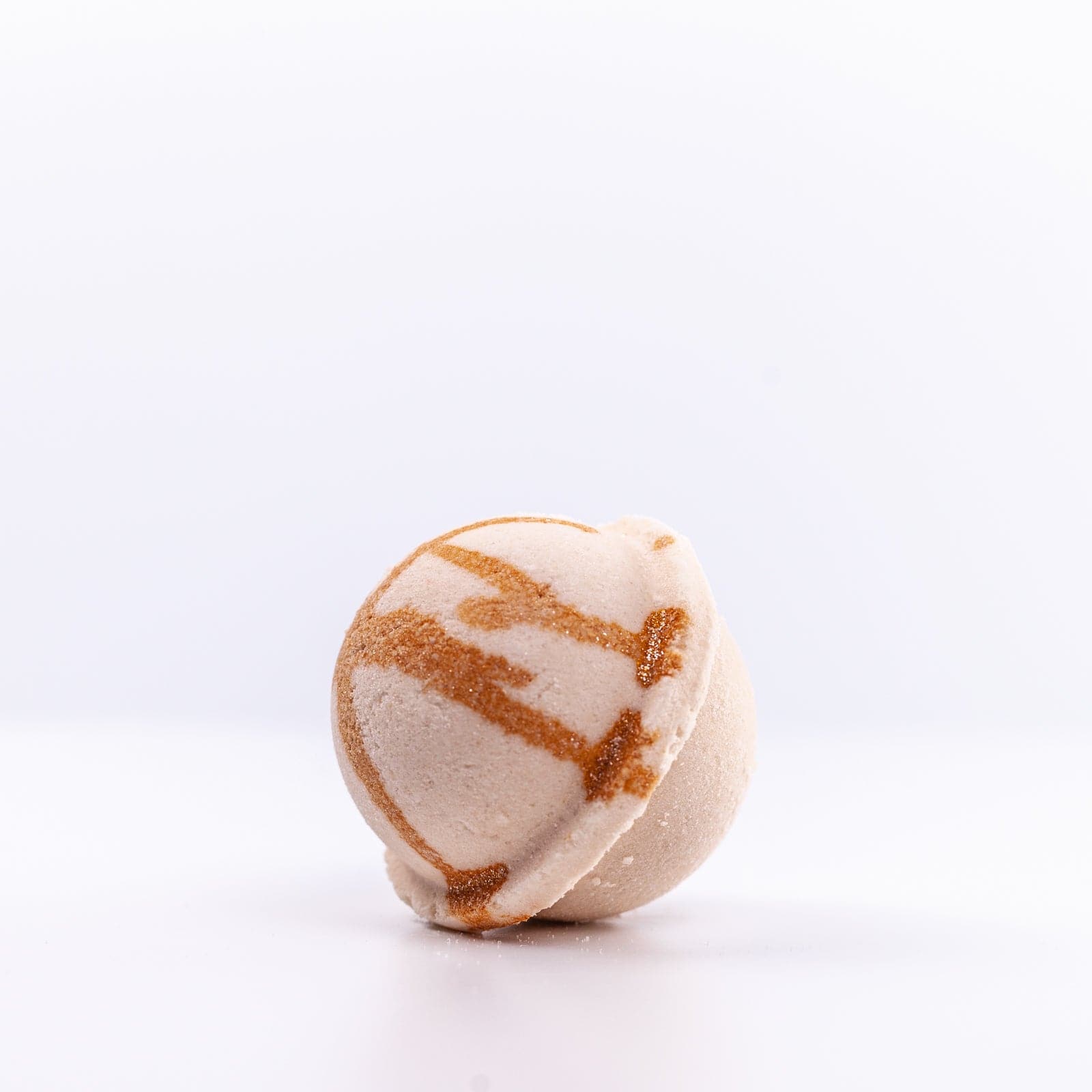Bronze and brown Oatmeal Honey Bath Bomb resting on side against white background